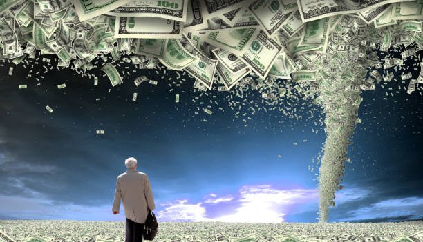 conceptual finance image of rear view businessman on money covered landscape looking at view with storm of money tornado